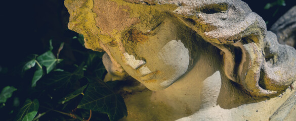 Close up beautiful sad angel as symbol of pain, death and end of life. Ancient statue.
