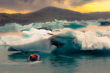 Iceland glacier Jokulsarlon. A man on a boat among the icebergs that broke away from the glacier