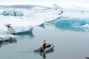 Iceland glacier Jokulsarlon. A man on a boat among the icebergs that broke away from the glacier