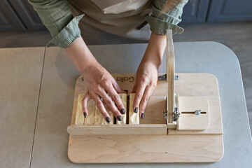 A woman makes handmade natural soap.The finished soap is cut into pieces using special machine. Home spa. Small business