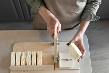 A woman makes handmade natural soap.The finished soap is cut into pieces using special machine. Home spa. Small business - obrazy, fototapety, plakaty