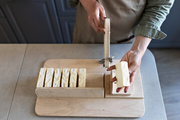 A woman makes handmade natural soap.The finished soap is cut into pieces using special machine. Home spa. Small business