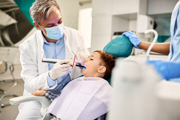 Small boy having dental filling drying procedure with curing UV light during dental appointment.
