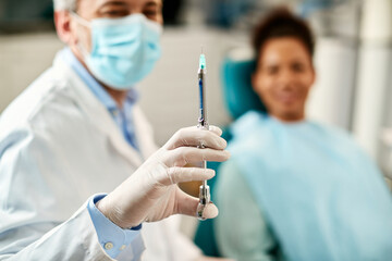 Close-up of dentist preparing anesthetic during patient's dental procedure.