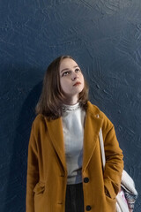 Portrait of a young teenager girl against a blue wall.