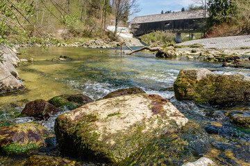 Alte gedeckte Holzbrücke über Fluss mit grünem Wasser