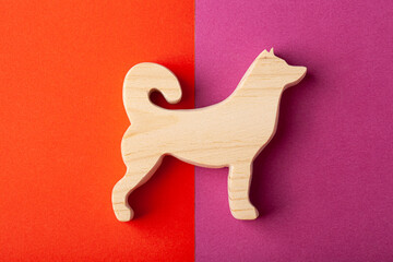 Figurine of a dog, a husky, carved from solid pine with a hand jigsaw. On a multi-colored background