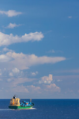 Obraz premium cargo ship nearby Capo Peloro Lighthouse in Punta del Faro on the Strait of Messina, most north eastern promontory of Sicily, Italy
