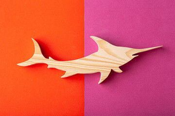 Figurine of a shark carved from solid pine by hand jigsaw. On a multi-colored background
