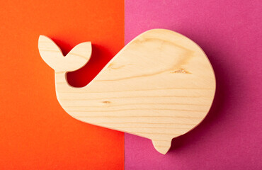 A figurine of a whale carved from solid pine with a hand jigsaw. On a multi-colored background