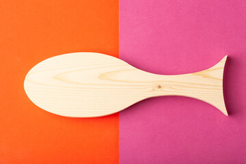 Figurine of horse mackerel carved from solid pine by hand jigsaw. On a multi-colored background