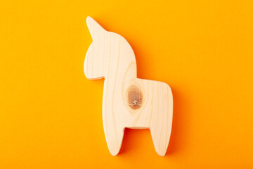 A figurine of a horse or unicorn carved from solid pine with a hand jigsaw. On a yellow background