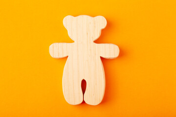 A toy bear figurine, carved from solid pine by a hand-held jigsaw. On a yellow background