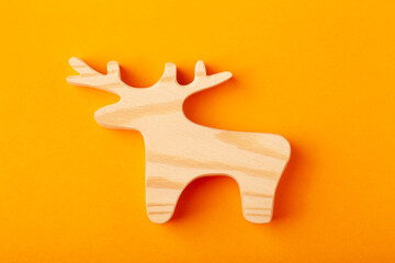 A figurine of a deer or elk carved out of solid pine with a hand jigsaw. On a yellow background