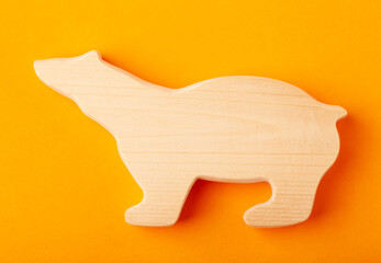 A figurine of a bear carved from solid pine by a hand jigsaw. On a yellow background