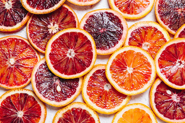 Bright colorful background of fresh ripe sliced blood oranges. Close up, flat lay, top view. Blood...