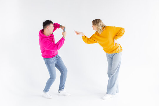 Image of a man take photo of his positive optimistic woman on white background by mobile phone.