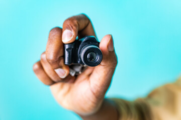 mini camera in hand of african american people in blue studio