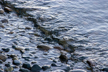 small waves flowing in over rocky shoreline
