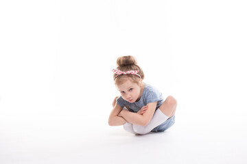 Childhood, emotions concept, little cute girl in a blue dress posing in the studio on a white