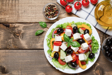 Greek salad with cheese and fresh vegetables on wooden background. Flat lay, top view, copy space