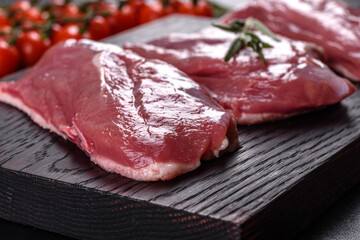 Raw duck breast with herbs and spices on a dark concrete background