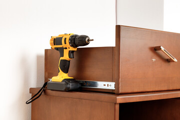 yellow screwdriver on a wooden table. power drill