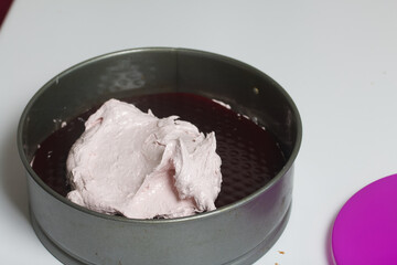 A woman prepares a marshmallow cake. Places a layer of jelly and marshmallows on the biscuit. Works with a mask and gloves.