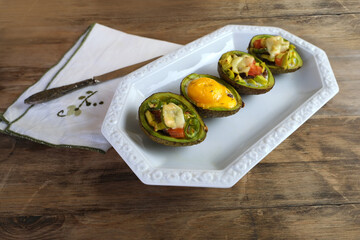 baked avocado stuffed with egg, vegetables, lie on a white dish, post-holiday detox, diet, healthy...