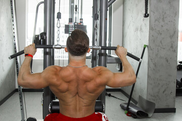 a man with big muscles is engaged in weightlifting in the gym. A pumped-up athlete goes in for...