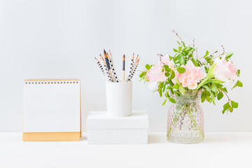 Mockup white desk calendar and pink tulips in a vase on a light background