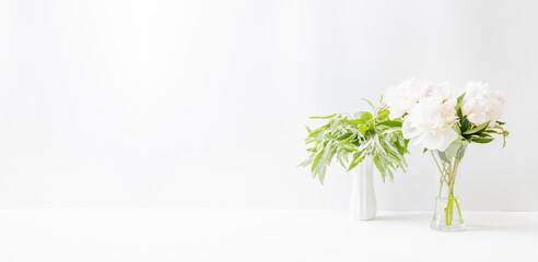 Minimalist home interior with decor elements. White peonies in a vase on a light background