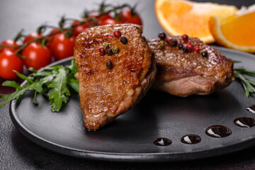Baked duck breast with herbs and spices on a dark concrete background
