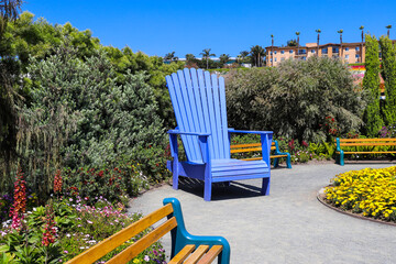 a giant blue wooden chair in the garden surrounded by colorful flowers and lush green trees and...