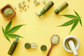Cosmetics with cannabis oil on a yellow background. Copy space, Flat lay composition with hemp lotion. mockup. Jar of hemp green  lotion. Cannabis cream with marijuana leaf