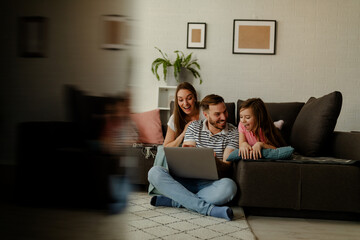 Obraz premium A picture of a happy family. A young family spends time at home playing video games on a laptop.