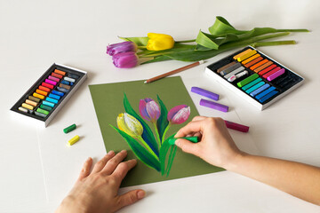 Soft pastel painting of flowers. With artist's hands. Top view