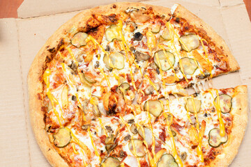 Close up Above top view of baked tasty hot and fresh homemade Pizza in the delivery box with cheese, mushrooms, meat, pickles, pepperoni