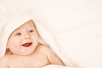 Fototapeta na wymiar Cute small boy lying at bed. Childhood bath concept. Light background. Smiling child. Happy emotion. Copyspace. Stay home. Towel mockup
