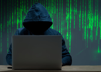 The hacker is in front of his computer. Digital figures in the background