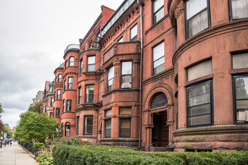 Fototapeta na wymiar Row of historic red-brick townhouses with fenced front yards on an overcast autumn day