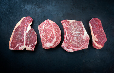 Raw dry aged wagyu porterhouse beef steak, entrecote and cutlet offered as top view on a rustic...