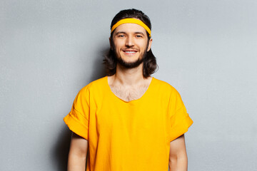 Portrait of young happy man in yellow shirt on background of grey wall.