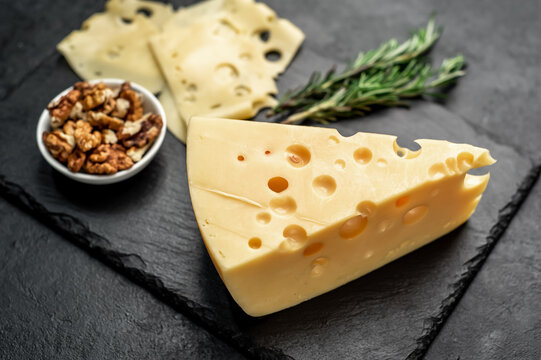 Maasdam cheese with walnut and rosemary on stone background