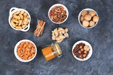 Obraz na płótnie Canvas Assortment of different nuts, healthy natural food concept, almonds, pecans, pistachios, cashews, walnuts and pine nuts, honey, cinnamon, high calorie food with vegetable protein and vitamins