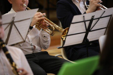 School band rehearsal. Students boys in a white shirt sitting playing a musical instrument trumpet...