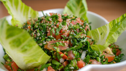 A bowl of delicious fresh Tabbouleh (tabbouli) salad with parsley, mint, tomato, onion, olive oil and lemon juice.