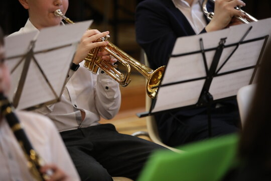 School band rehearsal. Students boys in a white shirt sitting playing a musical instrument trumpet clarinet on the notes.Close-up image