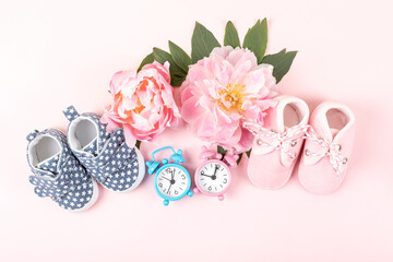 Girl and boy shoes with pink and blue watches on pink background. Baby birthday, invitation or greeting card mockup. Copy space. Flat lay.
