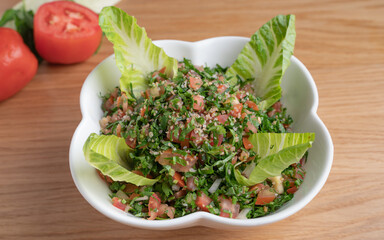 A bowl of delicious fresh Tabbouleh (tabbouli) salad with parsley, mint, tomato, onion, olive oil and lemon juice.